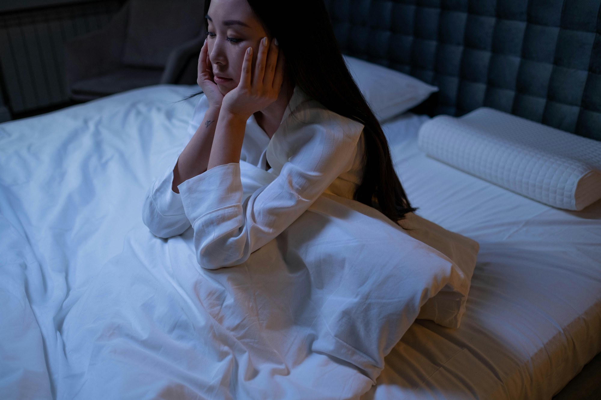 夜のベッドで眠れずにいる女性