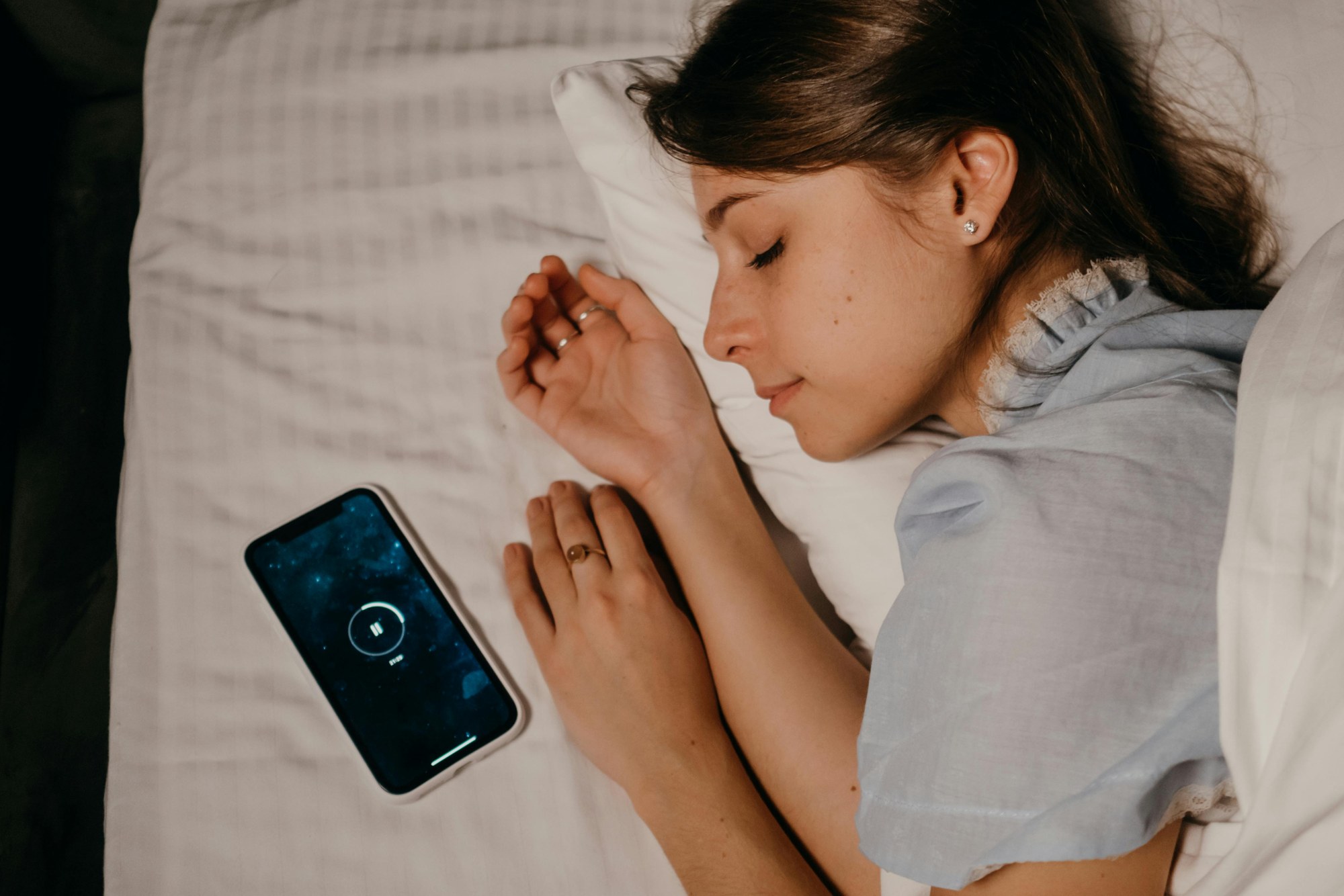 枕元にスマートフォンを置いて眠る様子